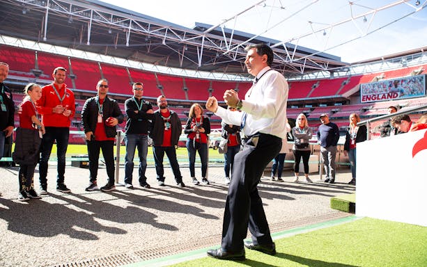 Tour group at Wembley Stadium, London, with guide explaining attractions.