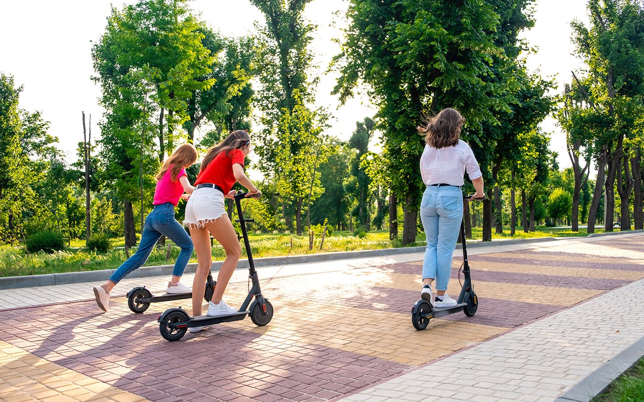 Scooter riders enjoying a tree-lined path during a private Imperial tour in Rome.