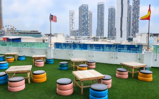 Rooftop seating area with colorful tire stools and tables, overlooking Shah Alam skyline.
