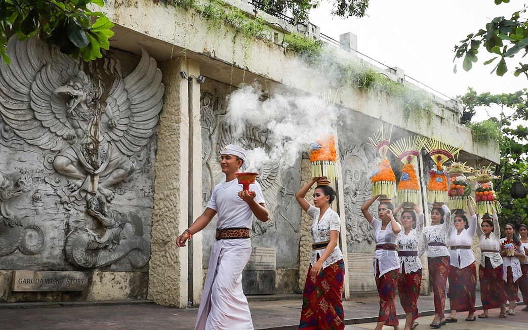 Balinese procession at Garuda Wisnu Kencana Culture Park, Bali, with traditional offerings.