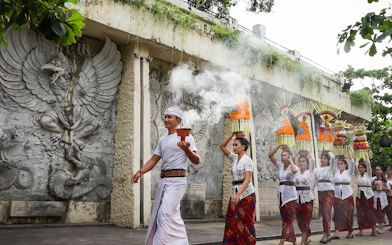 Balinese procession at Garuda Wisnu Kencana Culture Park, Bali, with traditional offerings.
