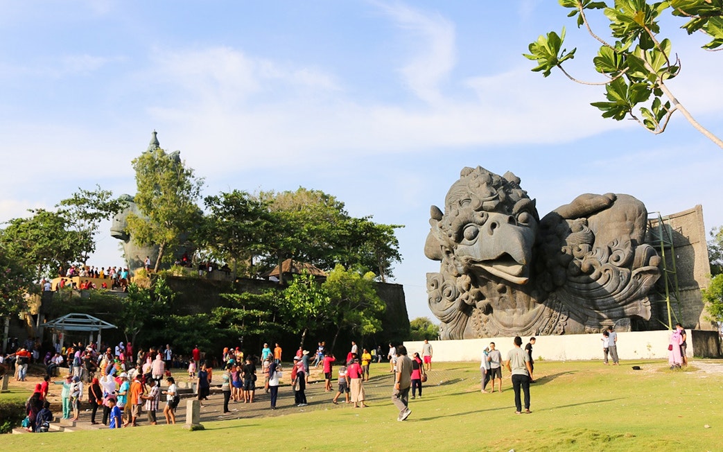 Visitors at Garuda Wisnu Kencana Culture Park, Bali, near large Garuda statue.