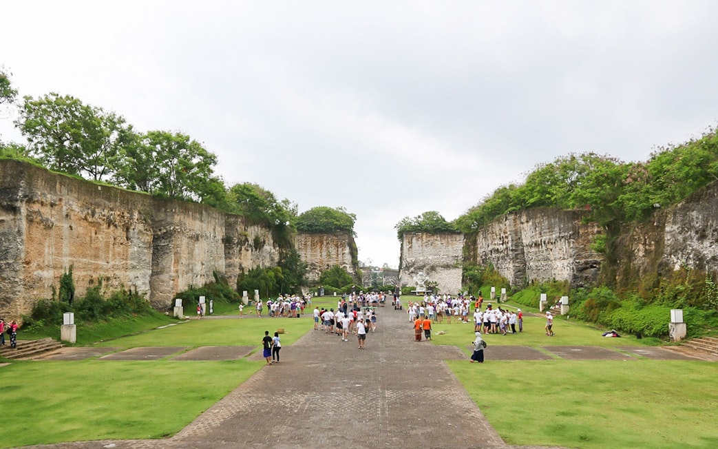 Visitors exploring limestone cliffs at Garuda Wisnu Kencana Culture Park, Bali.