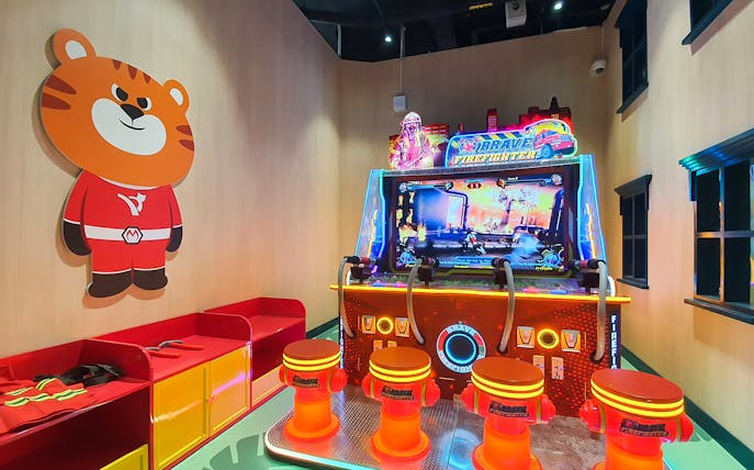 Arcade game area at Kiztopia Club Punggol with firefighting theme and cartoon tiger wall art.