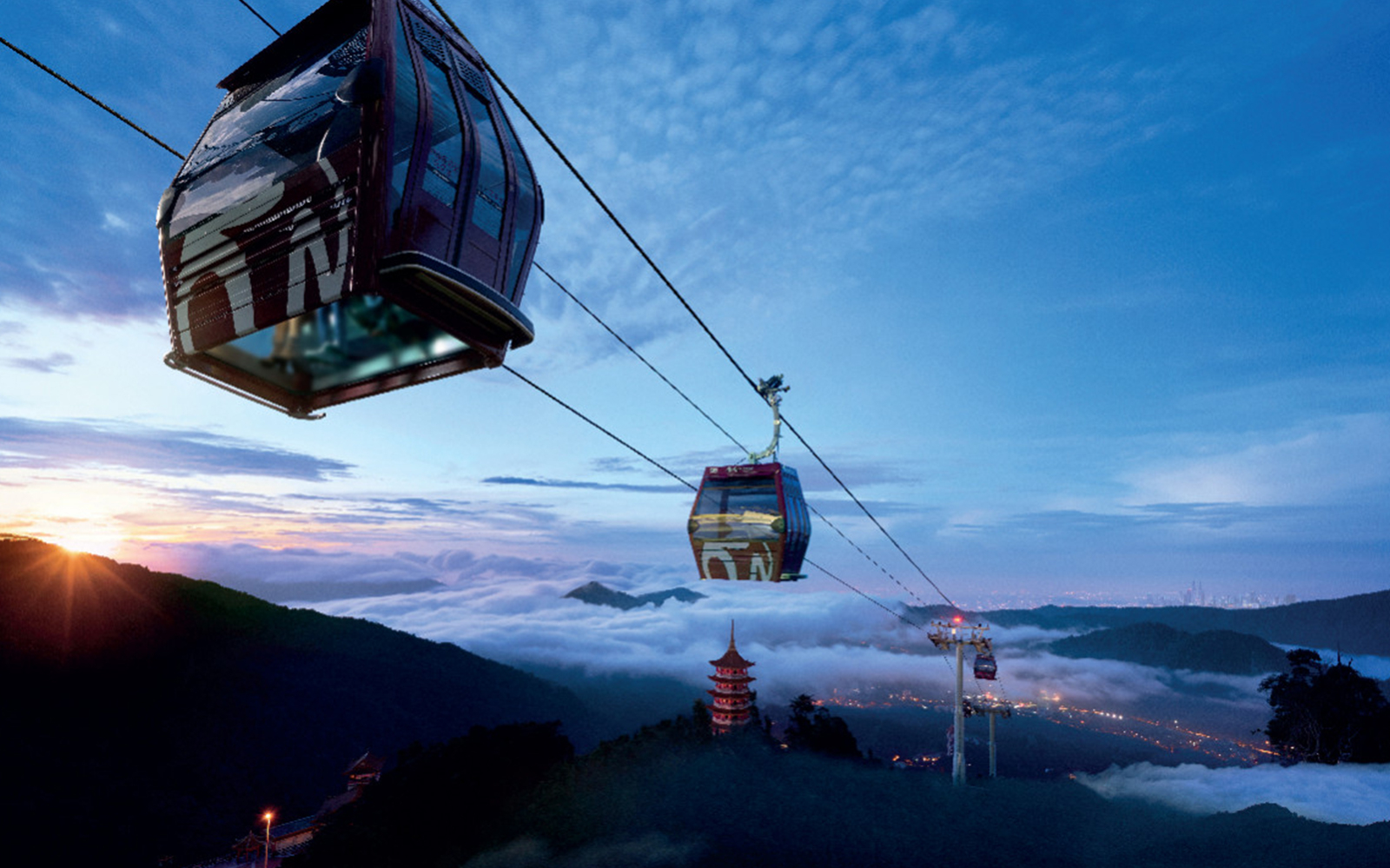 Genting Awana Skyway cable cars over misty mountains at sunrise.