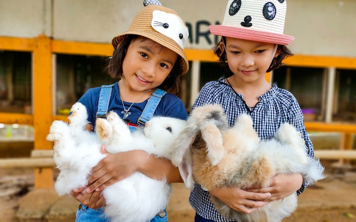 Children holding rabbits at Zoo Melaka petting area.