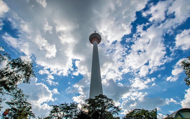 Kuala Lumpur Tower against a cloudy sky during the Half Day City Tour.