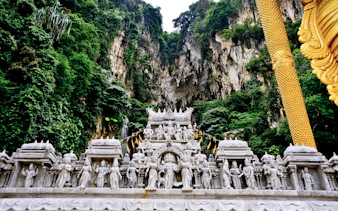 Batu Caves temple facade with intricate statues and lush limestone cliffs in Kuala Lumpur.