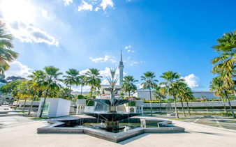 National Mosque of Kuala Lumpur with palm trees and fountain in foreground.