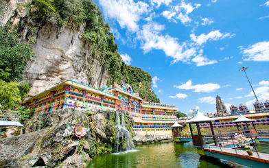 Colorful temple facade at Batu Caves, Kuala Lumpur, with limestone cliffs and blue sky.
