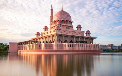 Putra Mosque reflecting in a lake under a blue sky in Kuala Lumpur.
