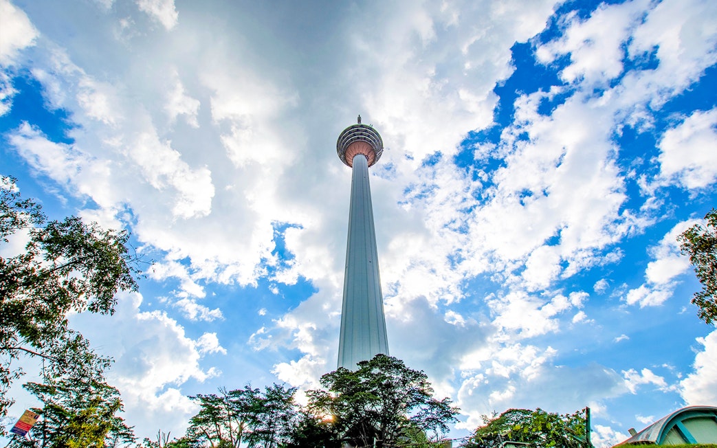 Kuala Lumpur Tower against a blue sky during a guided tour.