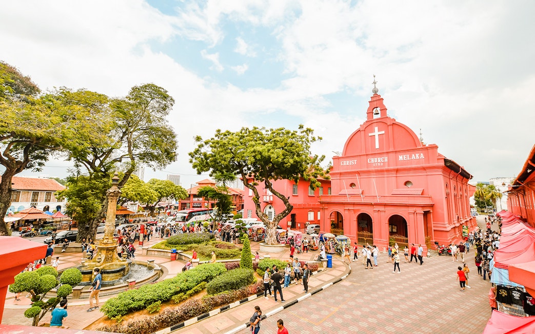 Christ Church Melaka with tourists exploring the historical site on a Melaka tour from Kuala Lumpur.
