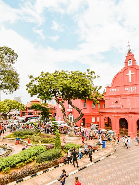 Christ Church Melaka with tourists exploring the historical site on a Melaka tour from Kuala Lumpur.