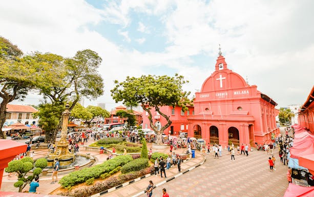 Christ Church Melaka with tourists exploring the historical site on a Melaka tour from Kuala Lumpur.