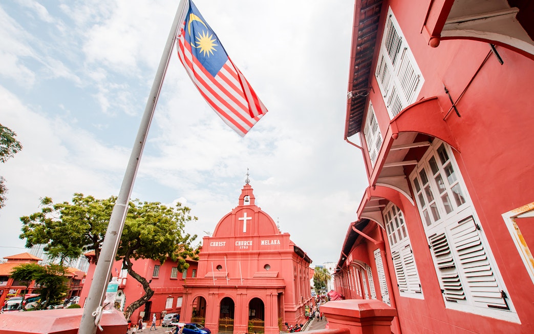 Christ Church Melaka with Malaysian flag, part of Historical Melaka Tour from Kuala Lumpur.