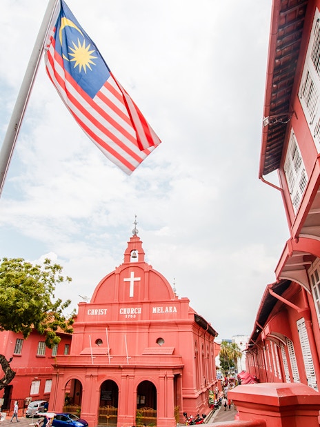Christ Church Melaka with Malaysian flag, part of Historical Melaka Tour from Kuala Lumpur.