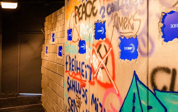 Graffiti-covered wall with TimeRide VR logos, part of Berlin's Time Travel Experience.