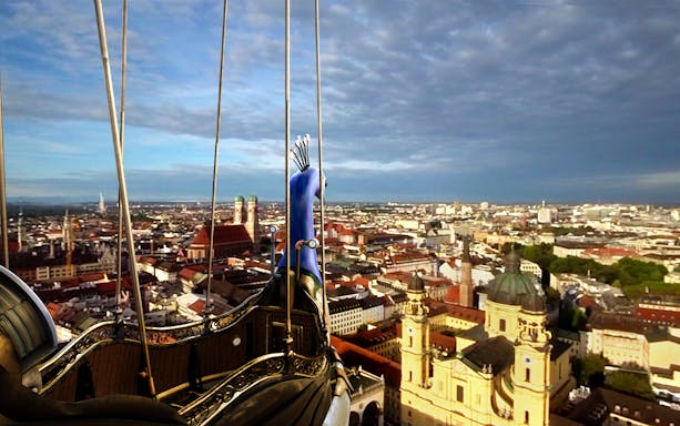 VR view of Munich skyline from a historic airship, featuring Frauenkirche and Theatinerkirche.