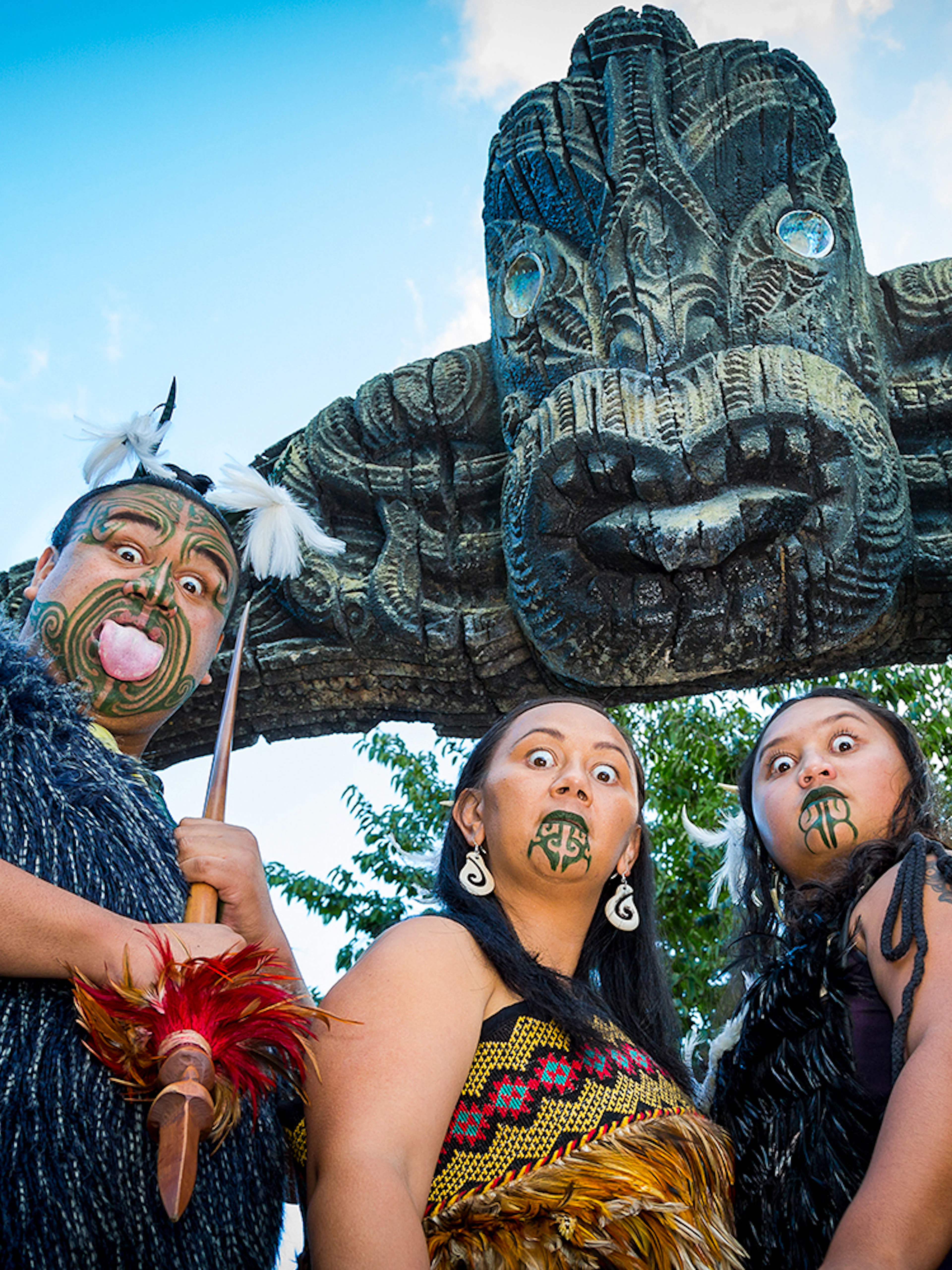Mitai Maori performers in traditional attire under carved arch, New Zealand.