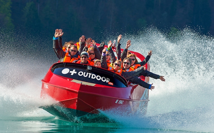Jetboat with passengers on Lake Brienz, Switzerland, creating water spray.