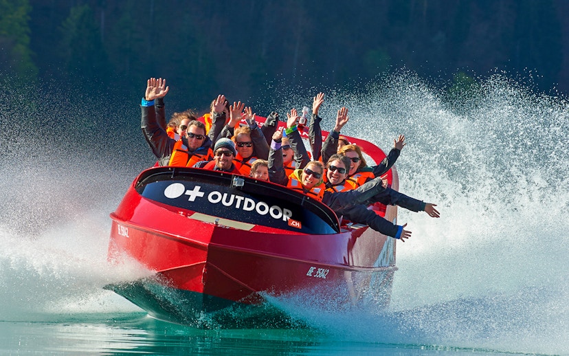 Jetboat with passengers on Lake Brienz, Switzerland, creating water spray.