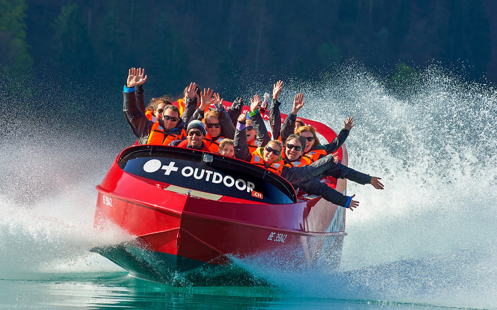 Jetboat with passengers on Lake Brienz, Switzerland, creating water spray.
