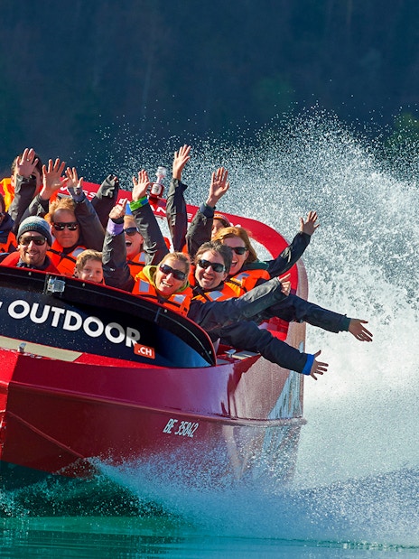 Jetboat with passengers on Lake Brienz, Switzerland, creating water spray.