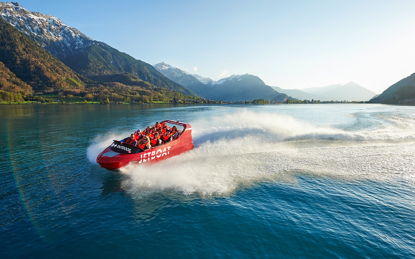 Jetboat speeding across Lake Brienz with scenic mountain backdrop, Interlaken.