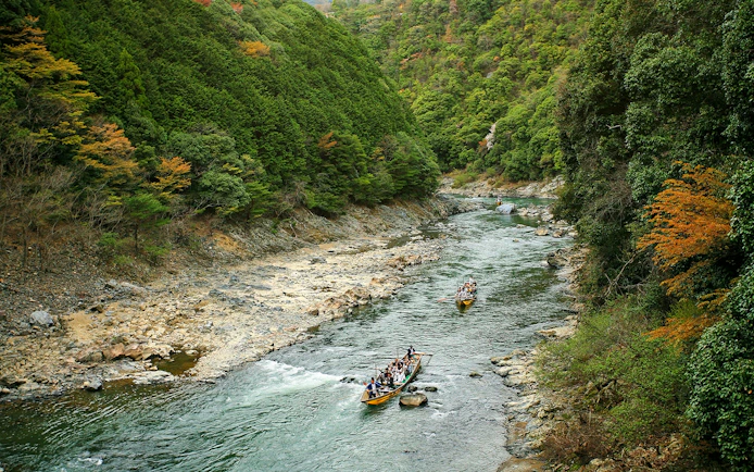 Boat ride on Hozugawa River surrounded by lush greenery in Kyoto, Japan.