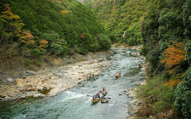 Boat ride on Hozugawa River surrounded by lush greenery in Kyoto, Japan.