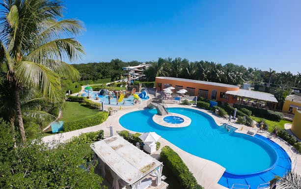 Playa Mia Grand Beach Park pool area with slides and palm trees in Cozumel, Mexico.
