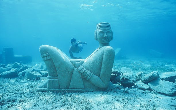 Underwater statue and snorkeler at Playa Mia Grand Beach Park, Cozumel.