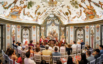 String quartet performing at Mozarthouse concert hall with ornate frescoes and audience seated.