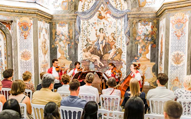String quartet performing at Mozarthouse concert with ornate frescoes in the background.