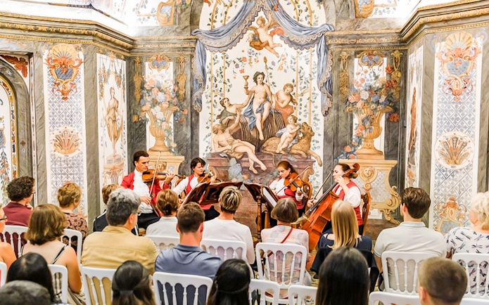 String quartet performing at Mozarthouse concert with ornate frescoes in the background.