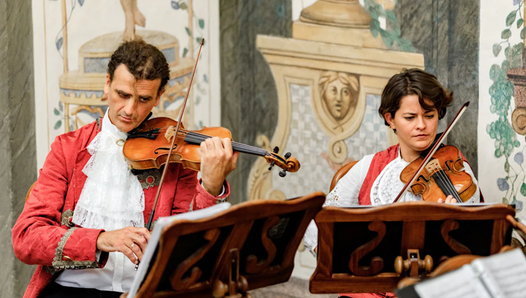 Musicians playing violins at Mozarthouse concert.