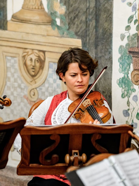 Musicians playing violins at Mozarthouse concert.