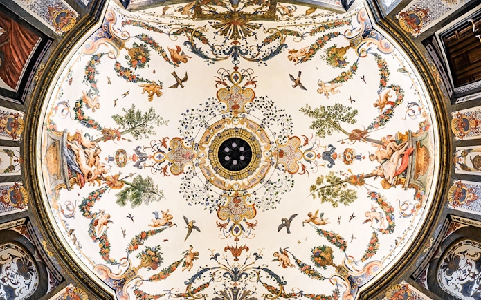 Ornate ceiling fresco at Mozarthouse concert venue, featuring cherubs and floral motifs.