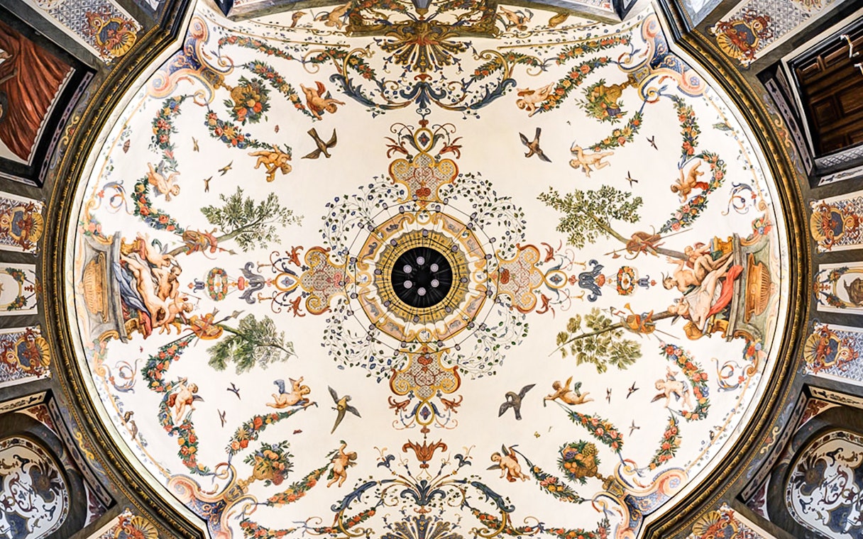 Ornate ceiling fresco at Mozarthouse concert venue, featuring cherubs and floral motifs.