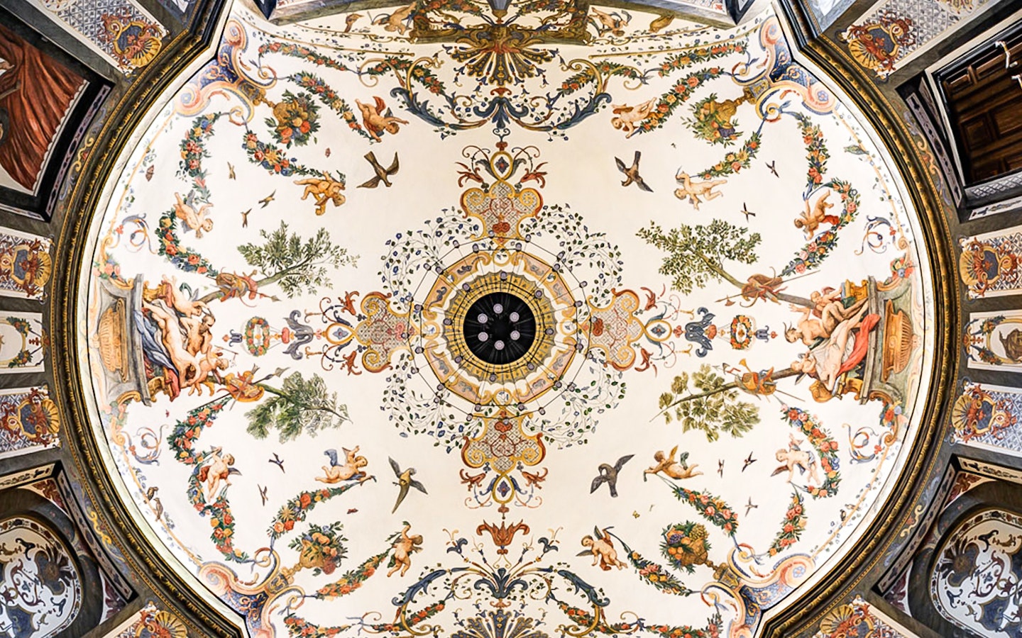 Ornate ceiling fresco at Mozarthouse concert venue, featuring cherubs and floral motifs.
