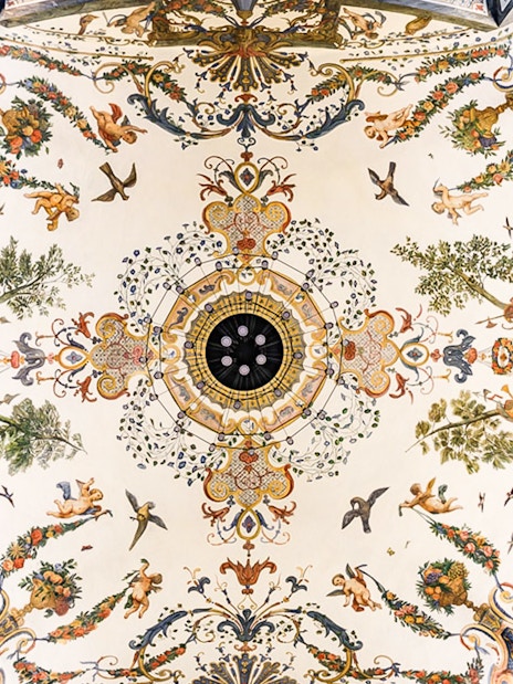 Ornate ceiling fresco at Mozarthouse concert venue, featuring cherubs and floral motifs.