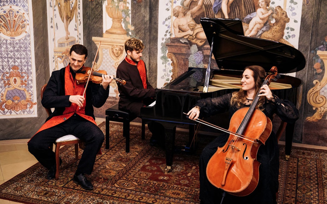 Musicians performing with violin, piano, and cello at Mozarthouse concert.