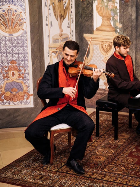 Musicians performing with violin, piano, and cello at Mozarthouse concert.