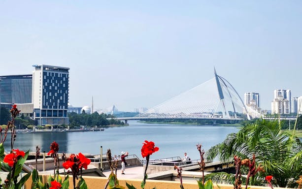 Putrajaya skyline with Seri Wawasan Bridge and lake, viewed from a garden.