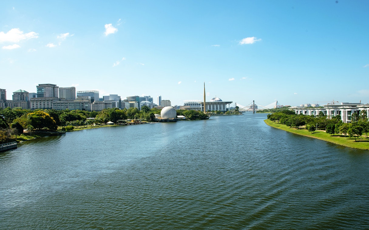 Putrajaya skyline with river view, featuring modern architecture and lush greenery.