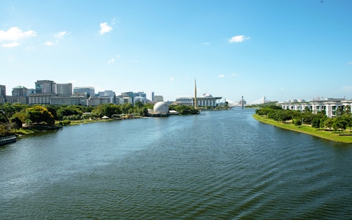 Putrajaya skyline with river view, featuring modern architecture and lush greenery.