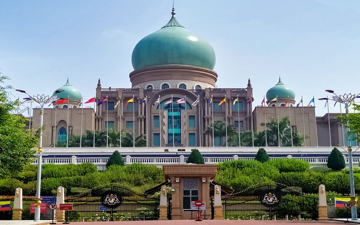 Putrajaya's Perdana Putra building with flags, seen on a traditional boat cruise.