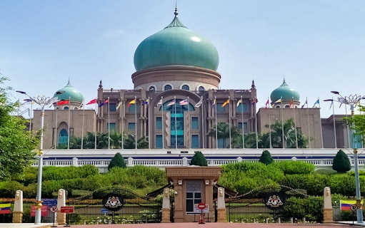 Putrajaya's Perdana Putra building with flags, seen on a traditional boat cruise.