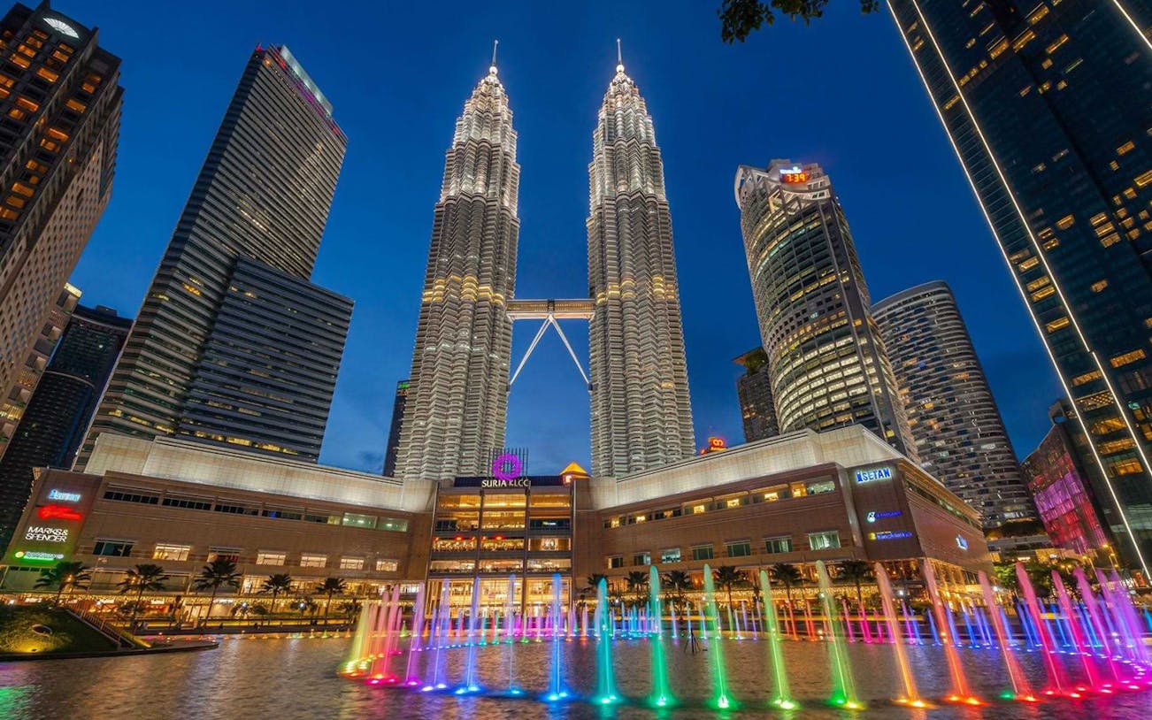 Kuala Lumpur Petronas Towers with colorful Symphony Water Fountain at night.